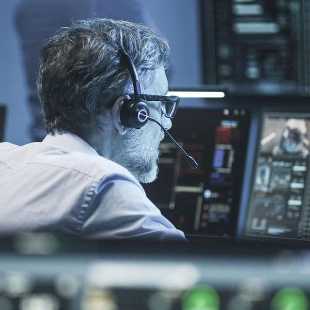 Ein Mann trägt ein Headset und schaut auf einen Bildschirm.