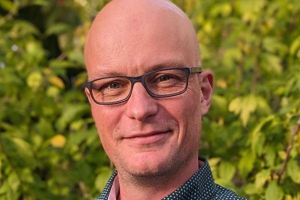 Portrait von Dominik Scherer vor grünem Naturhintergrund