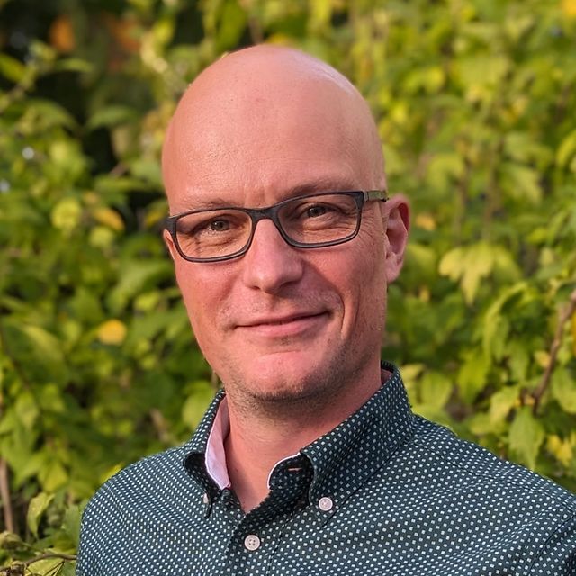 Portrait von Dominik Scherer vor grünem Naturhintergrund