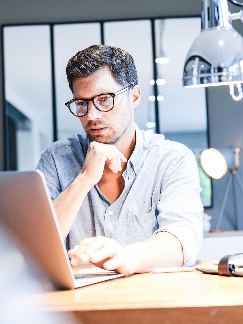 Mann sitzt vor einem Laptop und sucht nach weiterführenden Informationen zu Telematik Infrastruktur Lösungen