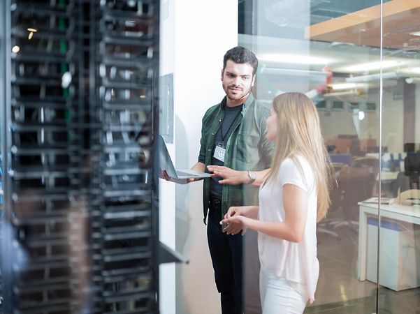Eine Frau und ein Servicetechniker stehen vor einem Serverschrank und sprechen über Business LAN – Cisco.