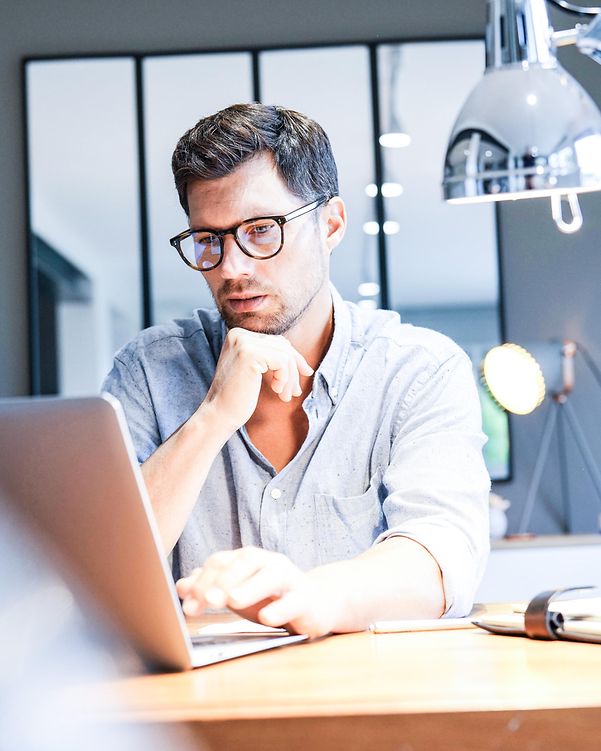 Mann mittleren Alters arbeitet an einem Laptop im Büro