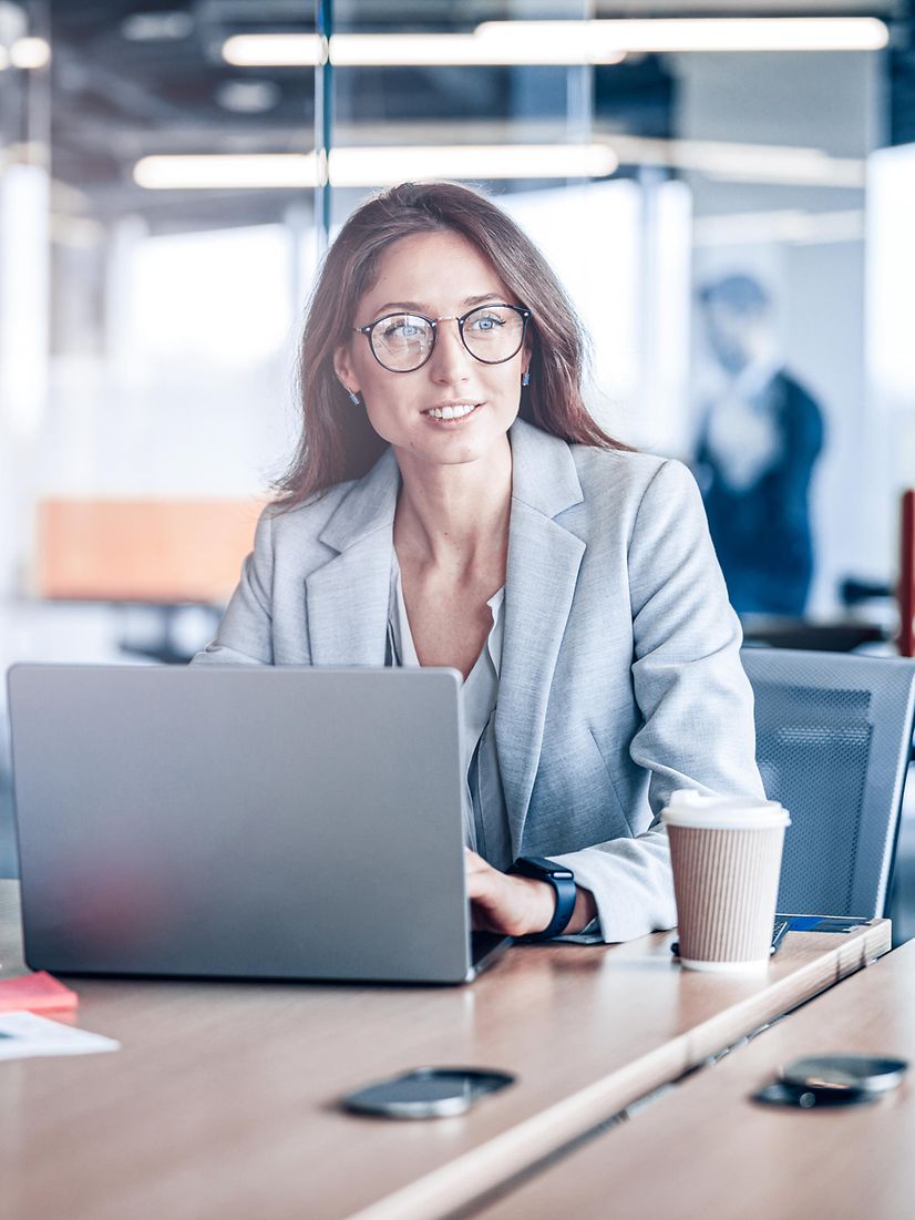 Eine Frau arbeitet im modernen Büro am Laptop zum Thema Salesforce Energy & Utilities Cloud