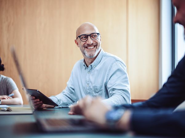 Lächelnder Mann mit Brille nutzt Phone für Microsoft Teams X
