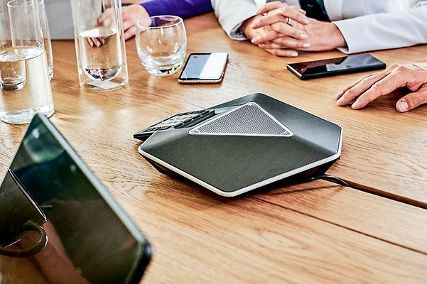Mehrere Smartphones liegen um eine Telefonspinne herum auf einem Meetingtisch
