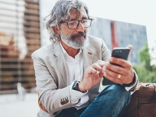Mann hält ein Handy in seiner Hand.