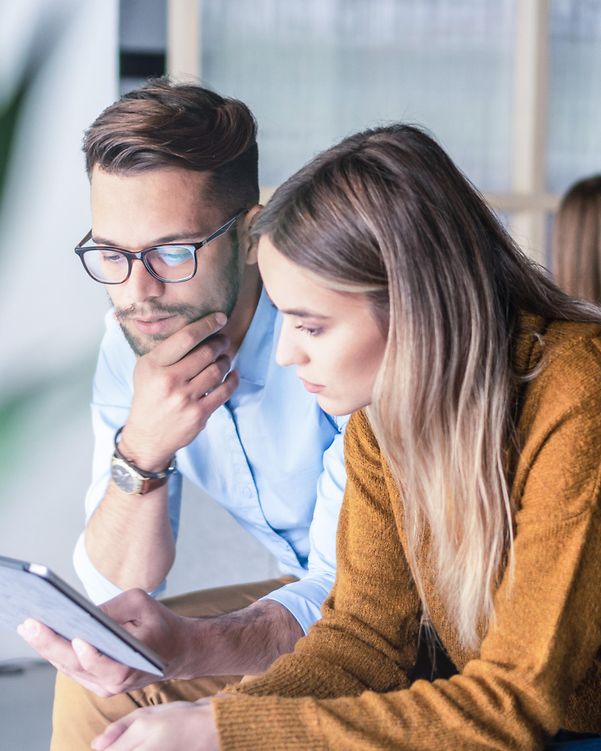 Zwei Personen schauen gemeinsam auf einen Laptop und nutzen Interactive Voice Response Business