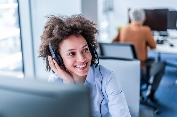 Eine junge Frau telefoniert mit einem Headset und berät zu Interactive Voice Response Business