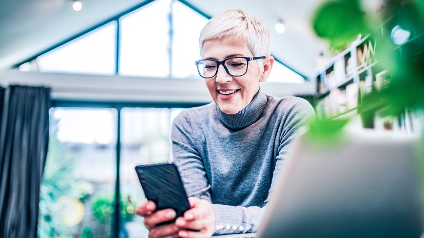 Eine Frau schaut im Büro auf ihr Smartphone