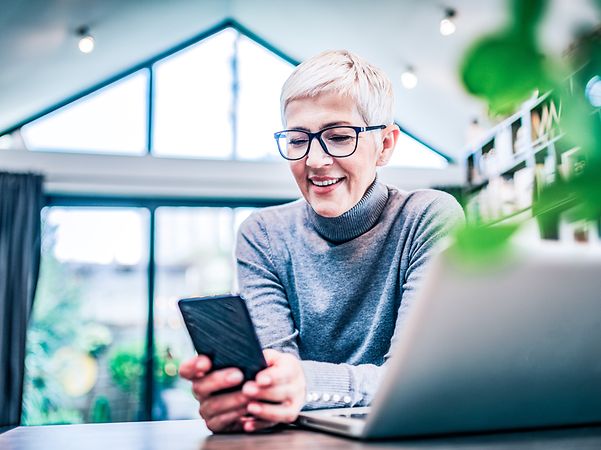 Eine Frau schaut im Büro auf ihr Smartphone