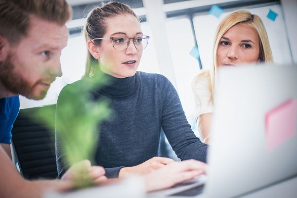 Eine Gruppe Kollegen schauen gemeinsam auf ein Notebook