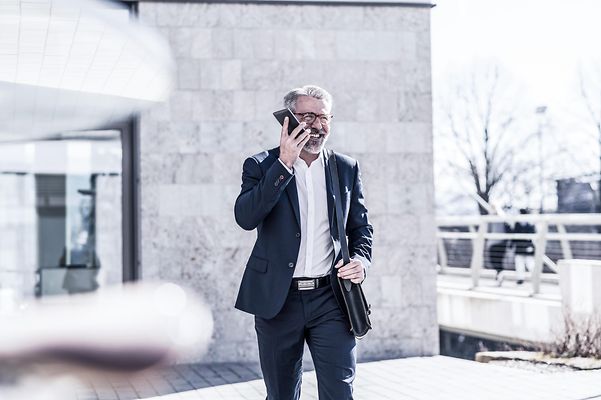 Ein Geschäftsmann telefoniert außerhalb eines modernen Gebäudes