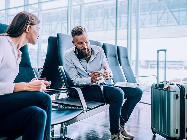 Zwei Personen sitzen am Flughafen und unterhalten sich miteinander.
