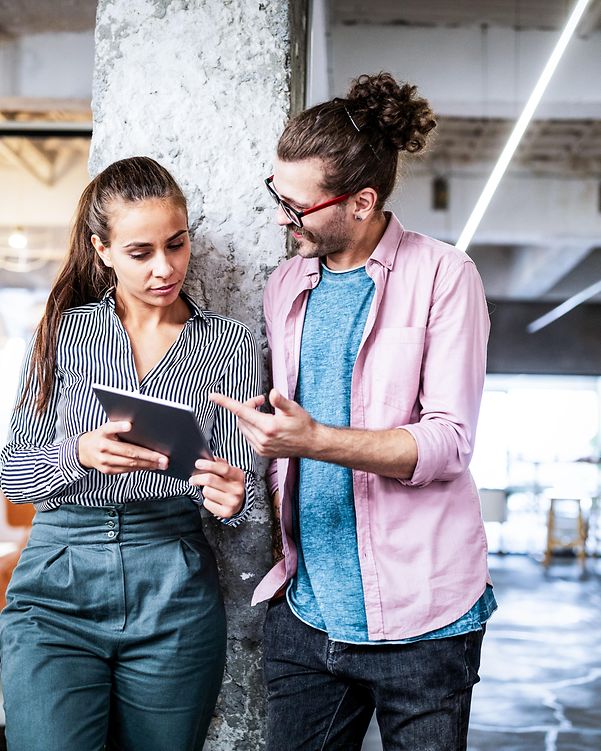 Zwei Personen mit Tablet diskutieren in einem modernen Büro über die SAP-Lösungen der Telekom für den Mittelstand.