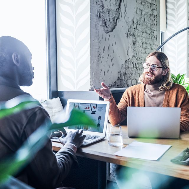 Kollegen sitzen im Büro und diskutieren über Zoom X Rooms
