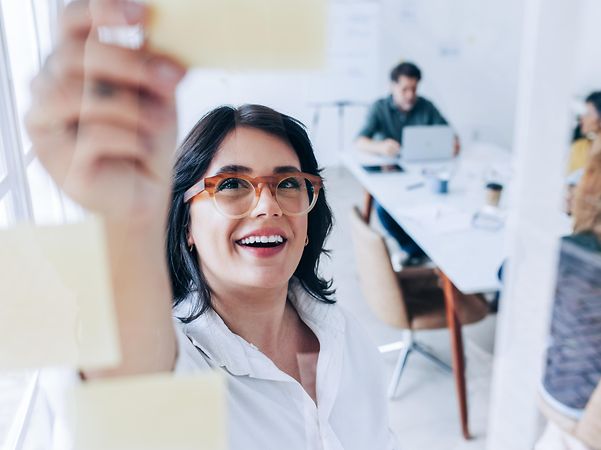 Frau im Meeting erläutert Kollegen die verschiedenen maßgeschneiderten IT-Infrastructure Lösungen für Geschäftskunden.