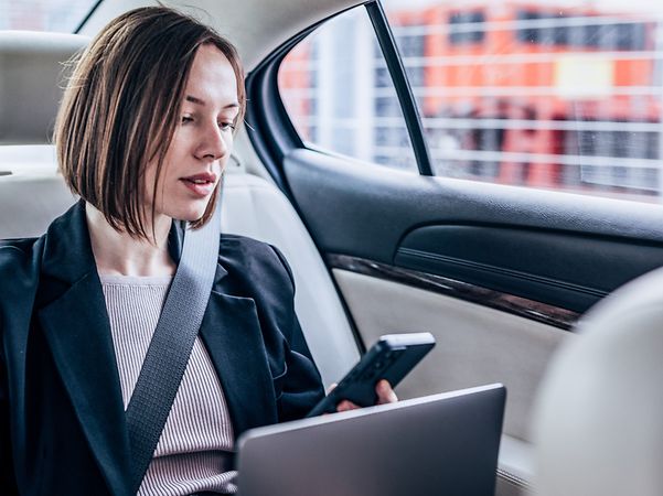 Business Frau mit Handy auf dem Rücksitz eines Autos nutzt einen Hotspot Drive.