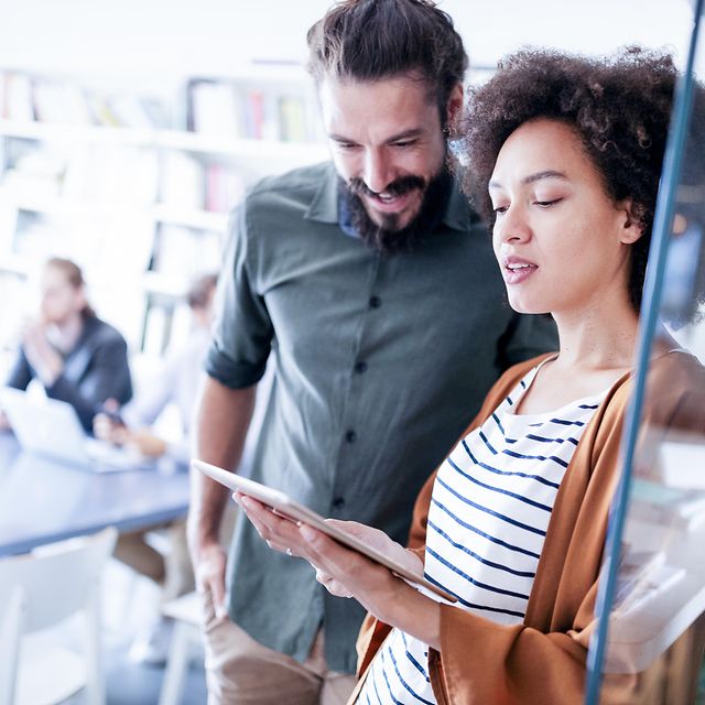 Mitarbeitende im Büro schauen sich auf einem Tablet den Internet und Festnetz Tarife Vergleich an