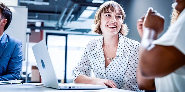 Geschäftsleute in Businesskleidung lächeln während der Diskussion bei einem Treffen im Büro