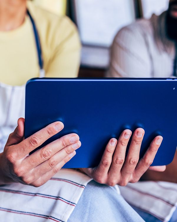 Business Analytics Eine Frau hält ein Tablett in Ihren Händen wärhend ein Mann neben Ihr sitzen darauf schaut