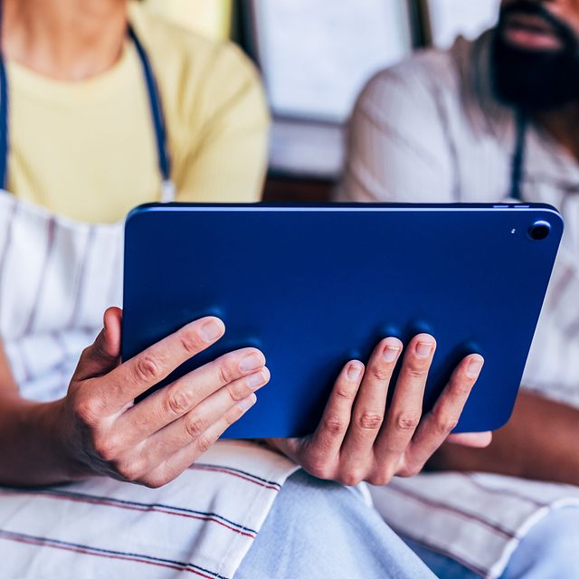 Business Analytics zeigt eine Frau, die ein ein Tablet in ihren Händen hält, während ein Mann neben Ihr sitzen darauf schaut.