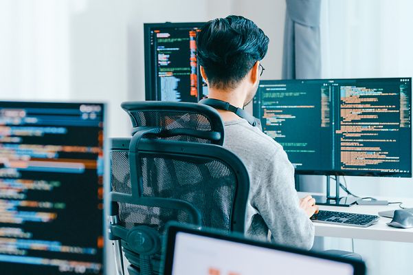 Junger erwachsender Mann arbeitet am Computer an einer Programierung.