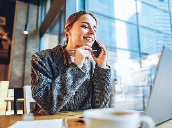 Frau sitzt vor ihrem Rechner und telefoniert und surft im besten 5G-Netz der Telekom