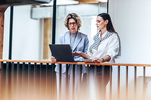 Zwei Frauen besprechen Inhalte am Laptop, unterstützt von stabiler Verbindung durch Mobile Optimization Pro.